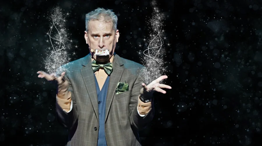 David Williamson surrounded by flying sparkles against a dark background